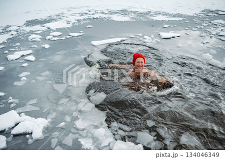 Elderly woman practicing outdoor ice bathing during winter season 134046349