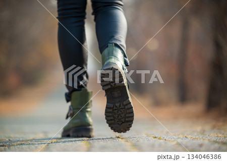 A woman wearing green boots is walking on a path A woman wearing green boots is walking on a path 134046386