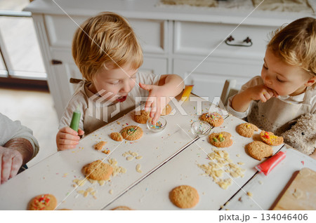 Happy children decorating Christmas cookies at home. 134046406