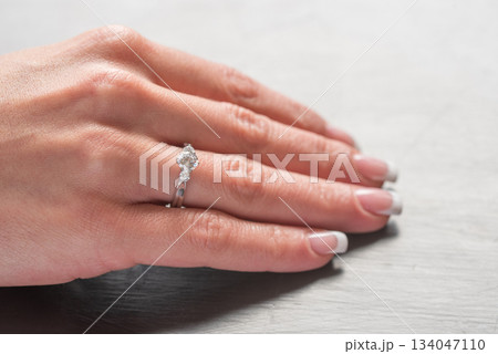 A woman's hand holding a ring with a diamond in the center A woman's hand holding a ring with a diamond in the center 134047110