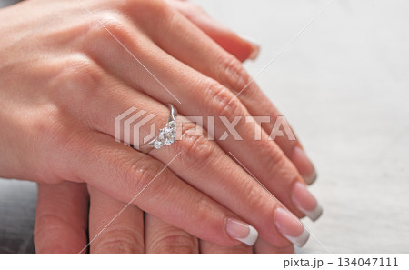 A woman's hand is holding a ring with three diamonds A woman's hand is holding a ring with three diamonds 134047111