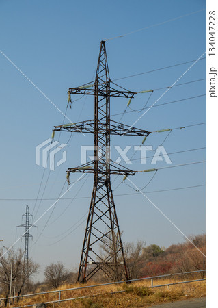 A tall power tower is surrounded by trees and wires A tall power tower is surrounded by trees and wires 134047228