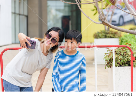 Mother child summer city family woman people street parent son enjoy bright urban outdoor selfie activity smiling with happiness capturing memorable moment together on bustling street background. Mother child summer city family woman people street parent son enjoy bright urban outdoor selfie activity smiling with happiness capturing memorable moment together on bustling street background. 134047561