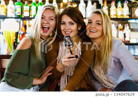 Women in bar singing karaoke Women in bar singing karaoke 134047629