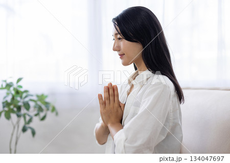 窓辺で合掌し目を閉じ瞑想する女性 134047697