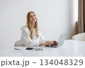 Young woman working on laptop in bright modern workspace during daytime 134048329