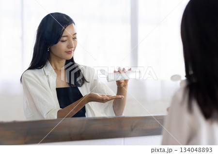 鏡の前で化粧水をつける女性 134048893
