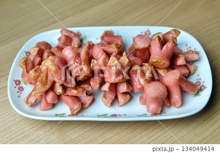 Decorative Fried Pink Sausages on White Platter 134049414