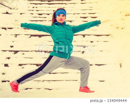 Woman wearing sportswear exercising outside during winter 134049444