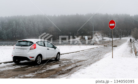 Winter Road with Car and No Entry Sign in Foggy Forest 134050395