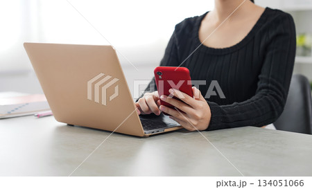 ノートパソコンとスマホを使って作業する女性 ノートパソコンとスマホを使って作業する女性 134051066