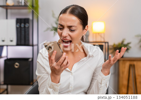 Young businesswoman argues on smartphone waves palm no no shows irritation and raises voice on call Young businesswoman argues on smartphone waves palm no no shows irritation and raises voice on call 134051188