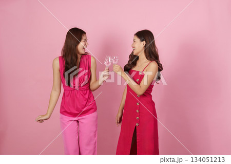Party Fun. Two friends toasting with drinks in a cheerful pink backdrop. 134051213