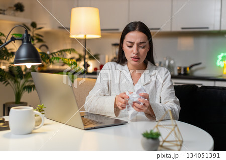 Young woman angry at utility bill crumples receipt throws papers worries about big charges evening 134051391