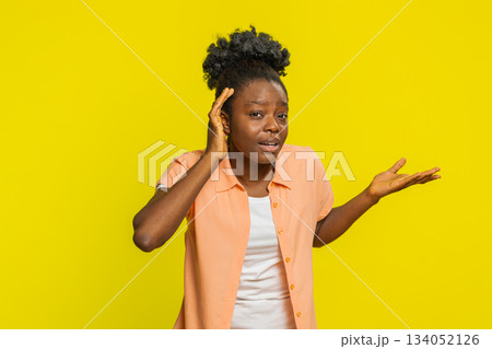 African American woman leaning forward, hand to ear, confused expression, trying to hear, surprised African American woman leaning forward, hand to ear, confused expression, trying to hear, surprised 134052126