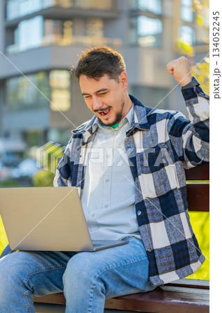 Overjoyed happy mature man working on laptop netbook screaming in delight on bench in downtown city Overjoyed happy mature man working on laptop netbook screaming in delight on bench in downtown city 134052245