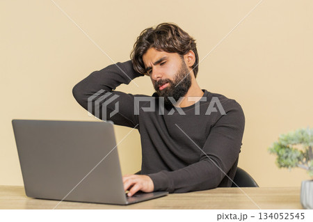 Young man using laptop at table loses becoming surprised sudden lottery results on beige background Young man using laptop at table loses becoming surprised sudden lottery results on beige background 134052545