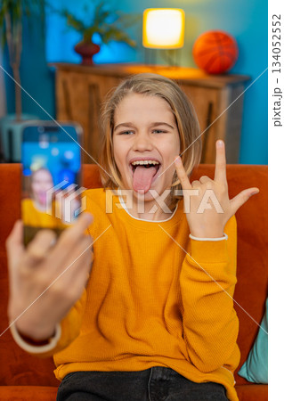 Teenager boy blogger taking selfie with smartphone, making funny facial expressions, posing at home Teenager boy blogger taking selfie with smartphone, making funny facial expressions, posing at home 134052552