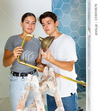 Young couple assembling shower before fixing to wall in apartment during refurbishment 134054676