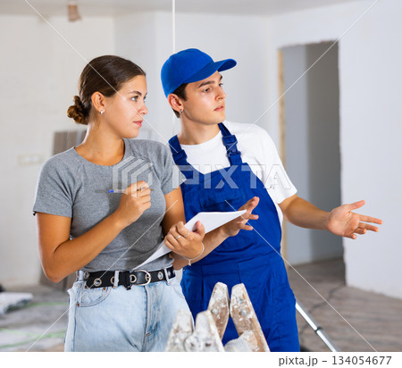 Female designer with papers talking to contractor in building during renovation 134054677