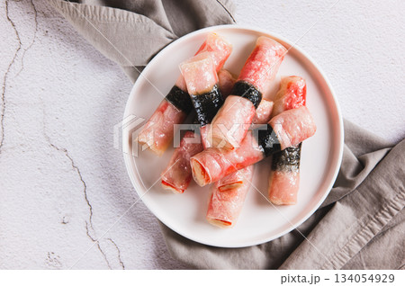 Close up of crab sticks in rice paper with nori fried in oil on a plate on the table top view Close up of crab sticks in rice paper with nori fried in oil on a plate on the table top view 134054929
