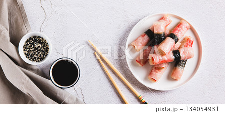 Fried spring rolls with crab sticks and nori on a plate on the table top view web banner Fried spring rolls with crab sticks and nori on a plate on the table top view web banner 134054931
