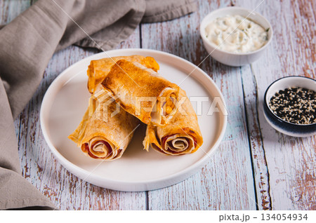 Tortilla, ham and cheese in baked rolls on a plate on the table 134054934