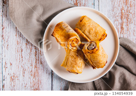 Close up of mini rolls of lavash, bacon and cheese on a plate on the table top view Close up of mini rolls of lavash, bacon and cheese on a plate on the table top view 134054939