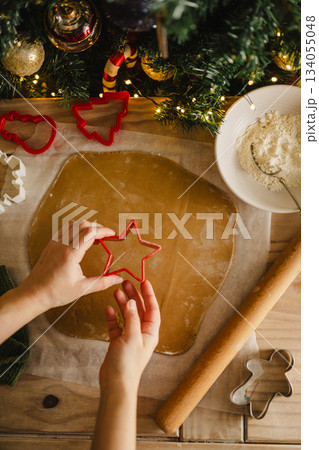 Holiday background. Woman holding cookie star cuter, cooking Christmas gingerbread cookies. Top view Holiday background. Woman holding cookie star cuter, cooking Christmas gingerbread cookies. Top view 134055048