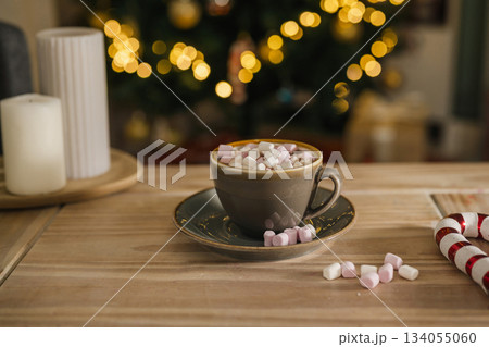 Holiday, Christmas background. A cup with hot chocolate and marshmallows on the table with Christmas tree on background 134055060