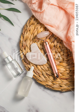 Rose quartz gua sha and massage roller tool for face massage and oil bottles, abstract beauty photo 134055087