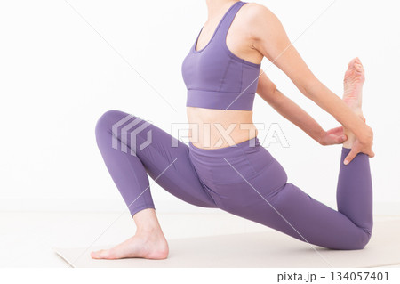 自宅でストレッチをするヨガウェア姿のミドル女性 自宅でストレッチをするヨガウェア姿のミドル女性 134057401