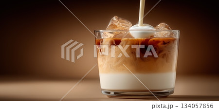 Milk pouring into a glass cup of black coffee, creating a dynamic splash and creamy layers. Milk pouring into coffee creating splash and swirl Milk pouring into a glass cup of black coffee, creating a dynamic splash and creamy layers. Milk pouring into coffee creating splash and swirl 134057856