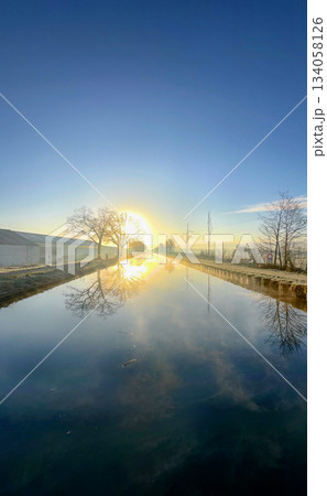 A Serene and Beautiful Reflection of a Sunrise Over a Tranquil Waterway in Nature A Serene and Beautiful Reflection of a Sunrise Over a Tranquil Waterway in Nature 134058126
