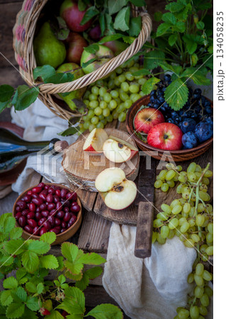 Autumn still life. Fruits and berries. Apples, grapes, strawberries, plums on a wooden table. Country style. Idle healthy vitamin food. Fruit harvest. Old knife. An apple in a basket. 134058235