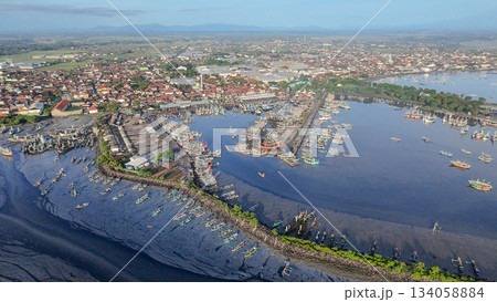 Aerial view of busy traditional fishing port in Muncar, Indonesia, featuring hundreds of boats and a sprawling coastal town. 134058884