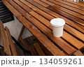 Coffee to go on wooden table, outdoors cafe. Takeaway white paper eco coffee cup 134059261