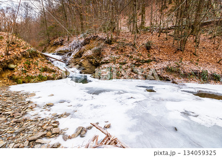 winter landscape with forest and frozen river. tranquil scene with beech trees near the shore of ice covered water stream through carpathian mountains. beautiful weather background or travel concept winter landscape with forest and frozen river. tranquil scene with beech trees near the shore of ice covered water stream through carpathian mountains. beautiful weather background or travel concept 134059325