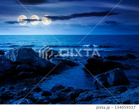 rocky shore of the sea coast under blue sky at night. beautiful view of coastal scene in full moon light. resort scenery during vacation season in summer. backdrop for fiction art or mystery concepts 134059337