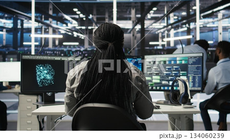 Data center programmer using artificial intelligence deep learning models to configure infrastructure. IT staff member works on AI programming language in server room, optimizing system, camera A 134060239