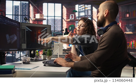 Two developers team interact with virtual AI assistant on PC to design a game hub, using machine learning to generate futuristic space station designs for a sci fi video game. Camera A. 134060448