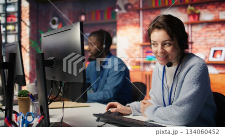 Teamworking cheerful call center agents tracking shipments in office. Upbeat customer center colleagues use software to locate clients packages and provide status updates, camera B close up Teamworking cheerful call center agents tracking shipments in office. Upbeat customer center colleagues use software to locate clients packages and provide status updates, camera B close up 134060452