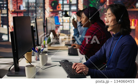 Multiethnic team of call center agents answering clients technical inquiries about hardware issue. Multiracial customer support workers in office doing job using PC to troubleshoot problems, camera B Multiethnic team of call center agents answering clients technical inquiries about hardware issue. Multiracial customer support workers in office doing job using PC to troubleshoot problems, camera B 134060455