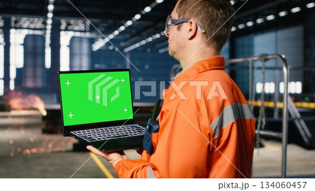 Green screen laptop with industrial staff in a workshop manages fabrication tools, showing engineering concepts, workforce responsibility and the heavy operation requirements. Green screen laptop with industrial staff in a workshop manages fabrication tools, showing engineering concepts, workforce responsibility and the heavy operation requirements. 134060457