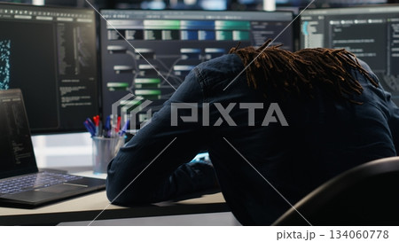 Angry server hub developer frustrated by slow data analytics AI generator. Annoyed data center worker punching desk, irked by glitching artificial intelligence program showing system metrics, camera B 134060778