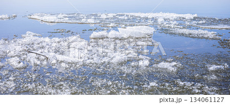 Ice fragments floating on calm water surface in serene natural environment Spring banner Ice fragments floating on calm water surface in serene natural environment Spring banner 134061127