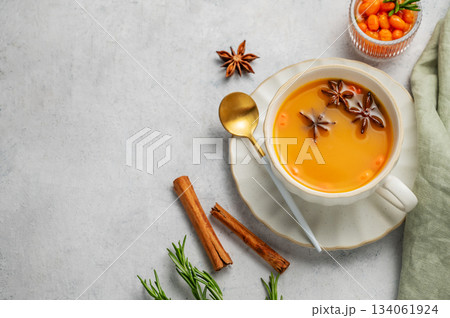 Sea buckthorn herbal tea in a cup on a light background with spices and berries. 134061924
