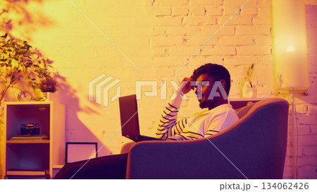 Man relaxing with laptop in cozy warm room Man relaxing with laptop in cozy warm room 134062426