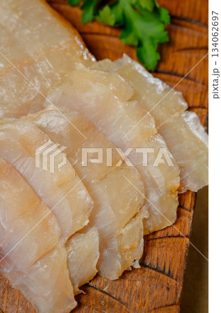 Sliced fillet of white smoked fish on a wooden board Sliced fillet of white smoked fish on a wooden board 134062697