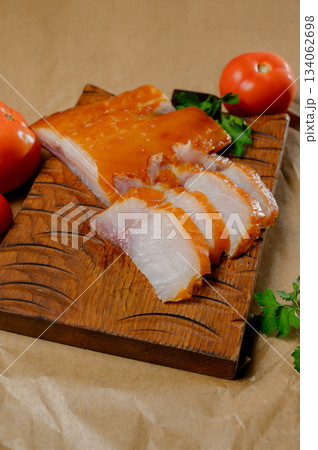 Sliced hot smoked fish fillet with a golden crust on a board Sliced hot smoked fish fillet with a golden crust on a board 134062698